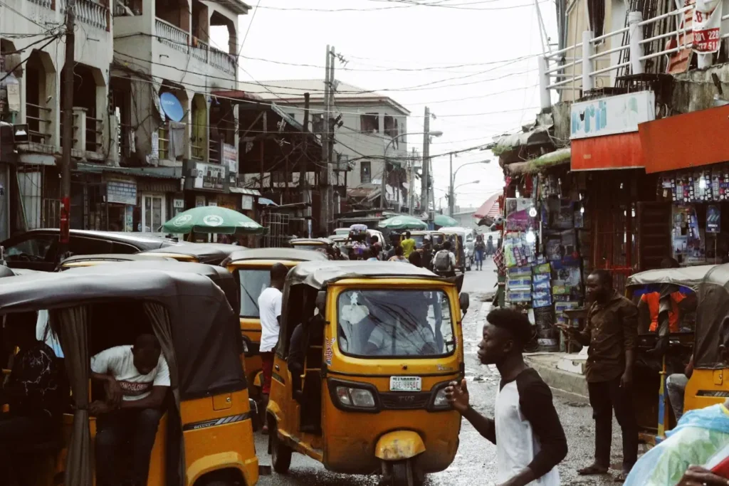 Busy Nigerian street with tricycle taxis